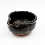 Small pouring bowl by Len Castle, stoneware with thickly poured speckled black saturated iron glaze over unglazed lower body, sold May 2025