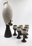 Ian Firth, Large wine bottle and six goblets, stoneware with speckled matte white glaze to the top halves and matte dark brown glaze to the stems, the bottle with wooden tap and cork lid (one goblet chipped)