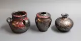 Three small stoneware vases by Graeme Storm, with manganese glaze with copper red and gold highlights, offered May 2025