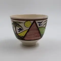 Hand-painted bowl by Warren Tippett, ceramic decorated in polychrome enamels and blue underglaze with stylised palms on a landscape, sold May 2025
