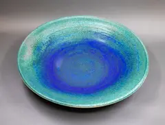 Wall charger by Graeme Storm, stoneware with mottled blue and green barium glaze, fitted with hanging wire, offered May 2025