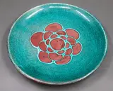 Stoneware dish by Graeme Storm, decorated with a copper red patterned centre on blue green ground, offered May 2025