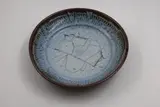 Shallow bowl by Len Castle, stoneware with light blue jun glaze over tenmoku (hairline crack), sold May 2025