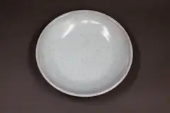 Pale celadon dish by Graeme Storm, porcelain, with copper red highlights to the exterior and base, offered May 2025