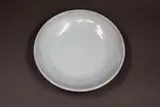 Graeme Storm, Pale celadon dish, porcelain, with copper red highlights to the exterior and base