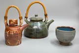Peter Stichbury, Two teapots and a tea bowl, the teapots with cane handles and wax resist decorations, the bowl with blue glaze over olive salt glaze