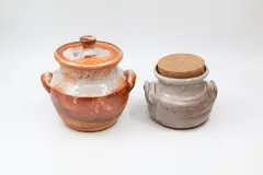 Andrew van der Putten, Two stoneware handled jars, the first with ceramic lid and crackle shino glaze with reddish tones, the second with a light toned shino glaze and cork stopper (one with hairline)