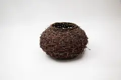 Coiled basket by Ruth Castle, woven rattan interlaced with twigs, sold Feb 2024