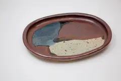 Unusual stoneware platter by Barry Brickell, of oval form, decorated with patches of black, grey, blue and tenmoku glazes to the centre, ca. 1960s, sold Feb 2024