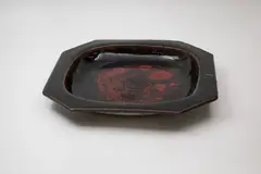 Octagonal platter by Len Castle, stoneware with red copper effects on tenmoku glaze, sold Feb 2024