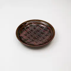 Stoneware dish by Graeme Storm, decorated with a tenmoku 'flower of life' wax resist design over dark olive glaze, offered Feb 2024