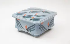 Merilyn Wiseman, Square lidded box, raised on four lug feet, with Mashiko-rock abstract decoration in blue, green and orange on a soft blue ground