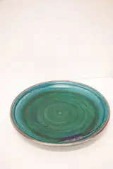 Large and impressive charger by Graeme Storm, stoneware with aqua green glaze with darker highlights and brown rim, pierced to the foot ring for wall suspension, sold Feb 2024