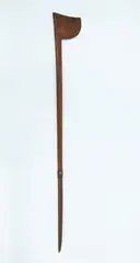 Tewhatewha, Long handled fighting staff, carved from medium brown wood, perforated hole on inner staff. Long tapered shaft, Wheku figure carved with shell inlaid eyes, almost halfway up. Small chip to butt end.