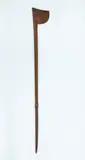 Tewhatewha, Long handled fighting staff, carved from medium brown wood, perforated hole on inner staff. Long tapered shaft, Wheku figure carved with shell inlaid eyes, almost halfway up. Small chip to butt end.