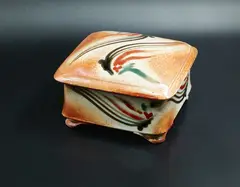 Merilyn Wiseman, Square lidded box, shino glazed earthenware with Mashiko-rock decoration in black, red and green on the exterior; the interior with delicate sage green glaze