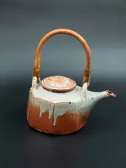 Teapot by Campbell Hegan, earthenware teapot of hexahedron body shape, with shino glaze and crackled effect, cane handle, spiraling motif on lid, , sold Oct 2023