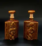 Parker Potteries, A pair of Lincoln Wines bottles, decorated with a tiki figure on one side and a manaia on the reverse, ceramic cork stopper