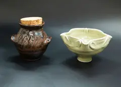 Small pedestal bowl and a handled jar by Mirek Smisek, the bowl with celadon glaze and applied decoration to the shaped sides, the jar with brown ash glaze, sold Oct 2023