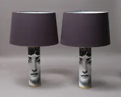 Fornasetti, Viso lamps, a pair of cylindrical metal lamps with hand-silkscreen design featuring the face of Lina Cavalieri, with brass detailing and black shades