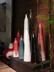 Nicholas Brandon, A collection of eight bottle form vases, each with long cylindrical bodies and small-lipped openings, various glaze effects