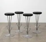Four bar stools by Piet Hein for Fritz Hansen, in tubular chrome plated pedestal base and with black leather upholstery, sold Jun 2022