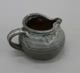 Small squat jug by Len Castle, stoneware with poured grey glaze over tenmoku, sold Jun 2022
