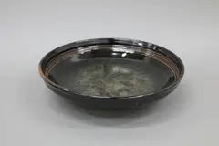 Large stoneware dish by Len Castle, with thick, dark tenmoku glaze with mottled grey and ‘bubbling’ effects to the well, sold Jun 2022