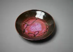 Stoneware dish by Len Castle, with gestural wax-resist decoration on tenmoku and purple glazes, sold Jun 2022