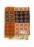Onehunga Woollen Mills, Te Ariki travel rug, with a tukutuku panel pattern in orange-brown, dark brown, mustard yellow and white (A/F)