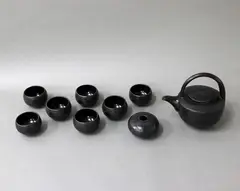 Anneke Borren, Black on black glazed tea set, comprising a large tea pot with crisscross decoration and seven cups with floral design; together with a small compressed circular vase