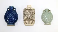Three Chinese snuff bottles, 20th century, comprising two similar porcelain ones with archaistic decoration, and a faux ivory one carved with Buddhist lions
