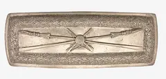 A silver belt buckle by Anton Teutenberg, decorated with crossed rifles and taiaha within a foliate scroll boarder., offered Dec 2012