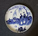 A Chinese porcelain plate, 19th century, painted in blue and white with ladies and children in a garden setting
