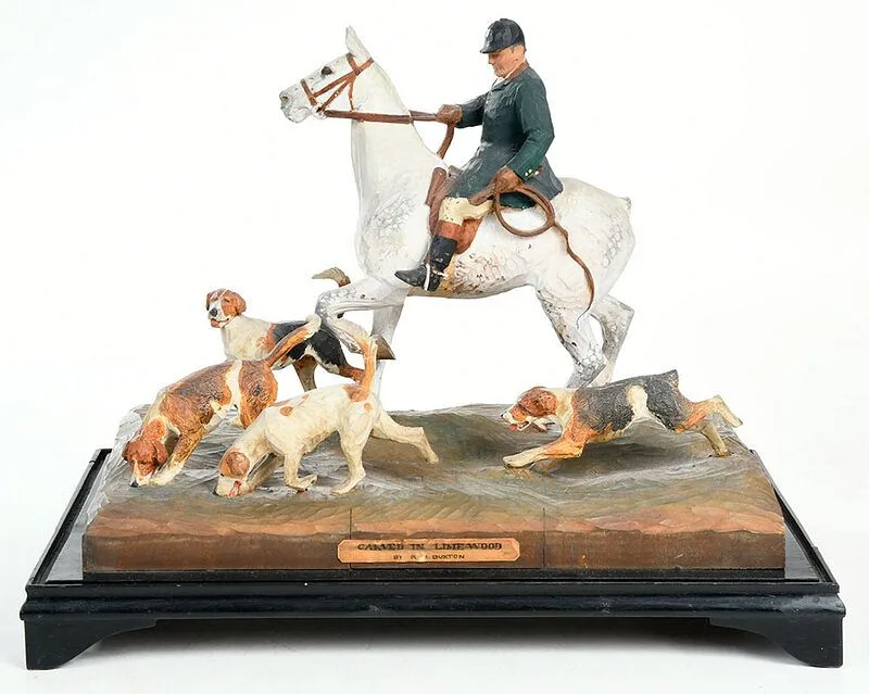 Untitled by R.H. Buxton, carved and painted scene of a hunter on horseback with hunting dogs, sold Jul 2020