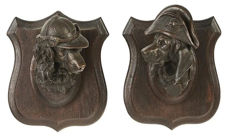Prosper Lecoutier, Pair of Dog pendant plaques: Hound in Napoleonic Hat and Spaniel in Cap, "Hound" cast signed "Lecourtier" and marked on collars "Serieys & Carlier, éd. rue N-D de Nazareth, patinated bronze mounted on shield-shaped wood plaques