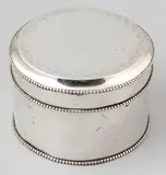 Zilveren koektrommel, rond, Rond model met parelrand en voorzien van florale gravure op de deksel, welke scharnierend is