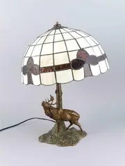 Tafellamp ca, edelhert, 1920 met een bulderend damhert van compositie metaal, bronskleurig gepatineerd met glas-in-lood kap 51cm