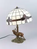 Tafellamp ca, edelhert, 1920 met een bulderend damhert van compositie metaal, bronskleurig gepatineerd met glas-in-lood kap 51cm