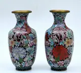 Pair Of Cloisonne Vases In Intricate Floral Design, Untitled, A pair of traditional Chinese Cloisonne vases with a distinctive black background adorned with vibrant flowers in shades of red, blue, pink, yellow and green, with fine gold colouring on the rims. Mid