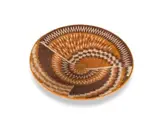 A Kavango coiled makalani palm leaf basket by Kavango Peoples Unrecorded artist, the grass binding with plant and root dyed spiral geometric patterns, sold Feb 2024