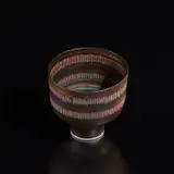 Footed bowl by Lucie Rie, circa 1976, Porcelain, golden manganese glaze with two terracotta bands crossed with vertical sgraffito lines and turquoise ring aro, sold Dec 2024