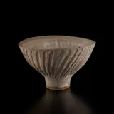 Large oval footed bowl with fluted design by Lucie Rie, circa 1978, Stoneware with manganese speckle, grey pitted glaze, sold Dec 2024