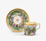 A KPM Berlin porcelain cup and saucer with vine leaf wreaths by Königliche Porzellanmanufaktur Berlin Kpm, Model no. 809. Blue sceptre mark with enamel blue dash above, red 98, press mark. Cup, sold Apr 2026