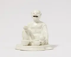 Meissen Royal Porcelain Manufactory, A Meissen porcelain figure of a crouching budai with a tea set