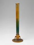 A tall, golden favrile glass vase with green overlay. by Tiffany Studios, On a bronze foot. Stamped to the underside: Tiffany Studios New York No 715. H, sold Nov 2015