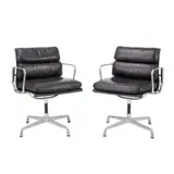 PAIR OF 'SOFT PAD' CHAIRS FOR HERMAN MILLER by Charles and Ray Eames, Black padded leather over an aluminium and metal frame on four point swivel base. Herman Miller mark embossed to frame, sold Feb 2025