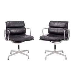 PAIR OF 'SOFT PAD' CHAIRS FOR HERMAN MILLER by Charles and Ray Eames, Black padded leather over an aluminium and metal frame on four point swivel base. Herman Miller mark embossed to frame, sold Feb 2025