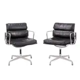 PAIR OF 'SOFT PAD' CHAIRS FOR HERMAN MILLER by Charles and Ray Eames, Black padded leather over an aluminium and metal frame on four point swivel base. Herman Miller mark embossed to frame, sold Feb 2025