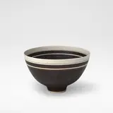 Lucie Rie, Footed bowl, circa 1965, Porcelain, alternating manganese and unglazed banding with single thin inlaid band near rim